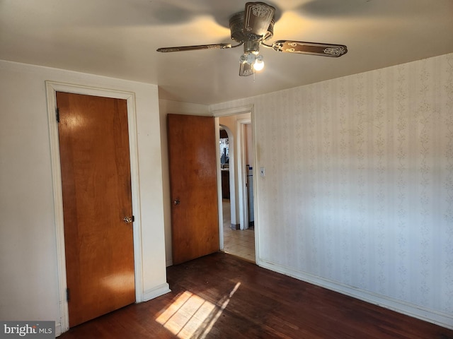 unfurnished bedroom with ceiling fan and dark wood-type flooring