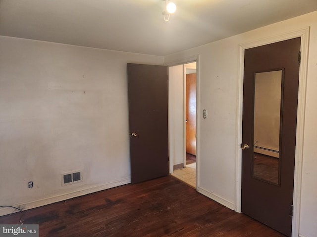 spare room with hardwood / wood-style flooring and a baseboard heating unit