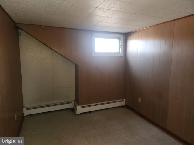 basement with wooden walls and a baseboard heating unit