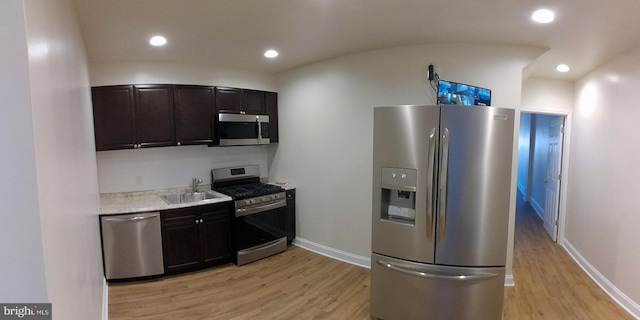 kitchen with sink, dark brown cabinetry, appliances with stainless steel finishes, and light wood-type flooring