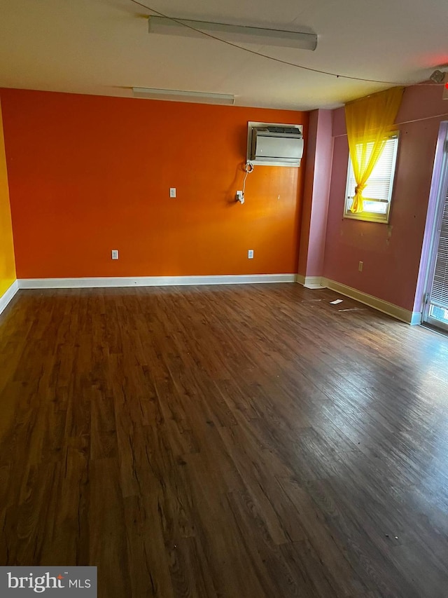 spare room featuring an AC wall unit and dark wood-type flooring