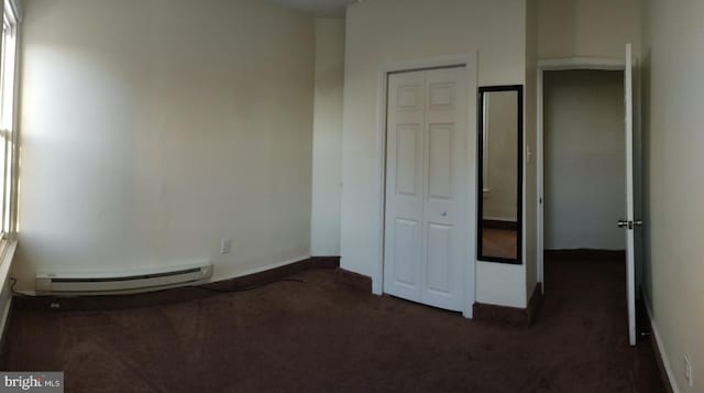 unfurnished bedroom featuring baseboard heating and dark colored carpet