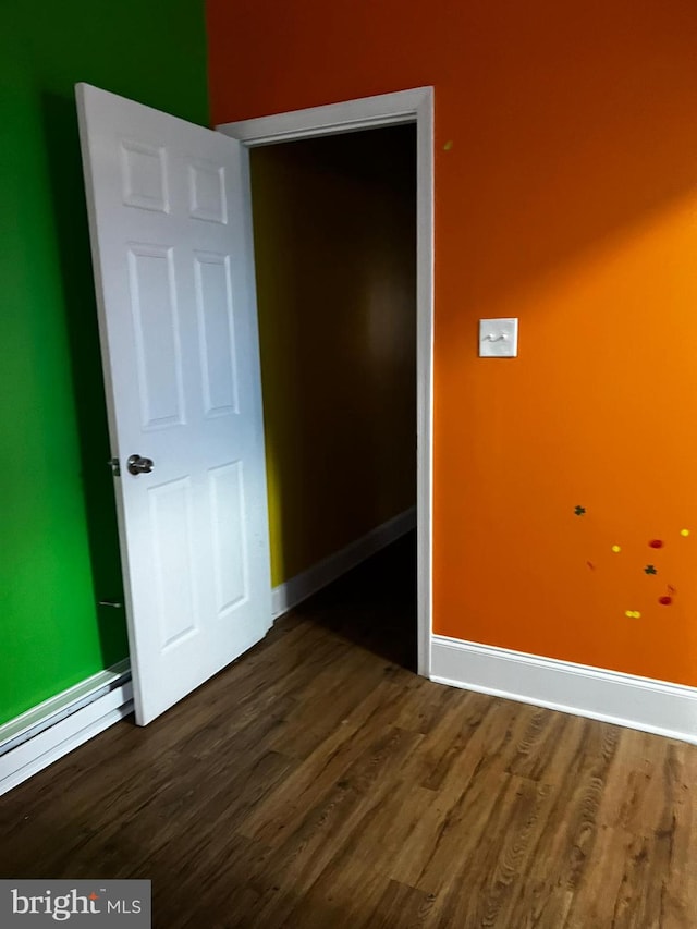 empty room with a baseboard radiator and dark wood-type flooring