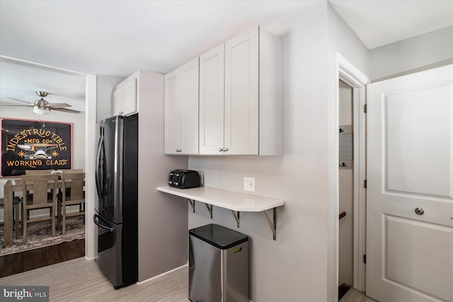 kitchen with stainless steel refrigerator, white cabinetry, ceiling fan, and light hardwood / wood-style floors