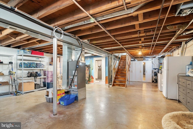 basement featuring heating unit and white fridge