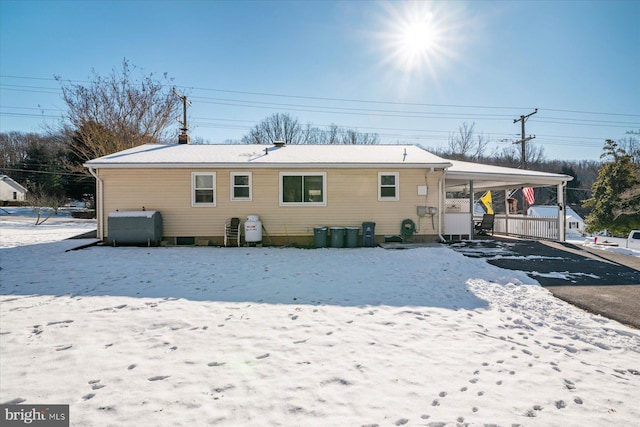 snow covered back of property with a carport