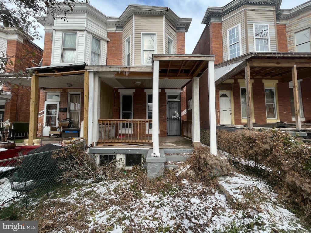 snow covered house featuring a porch