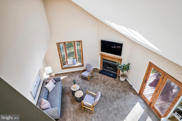 carpeted living area with a fireplace with flush hearth, high vaulted ceiling, and baseboards