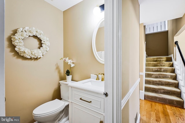 half bath featuring vanity, wood finished floors, and toilet