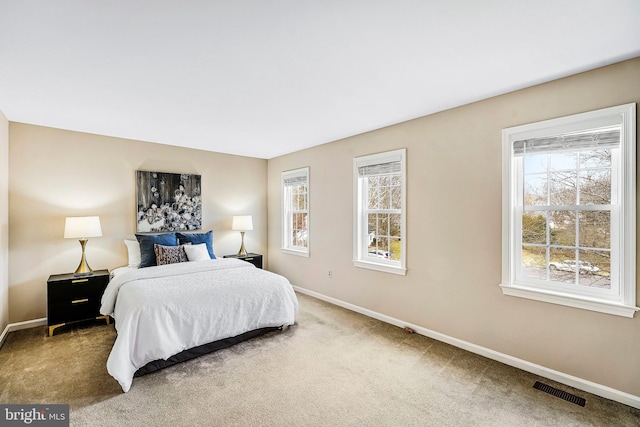 bedroom with carpet floors, multiple windows, visible vents, and baseboards