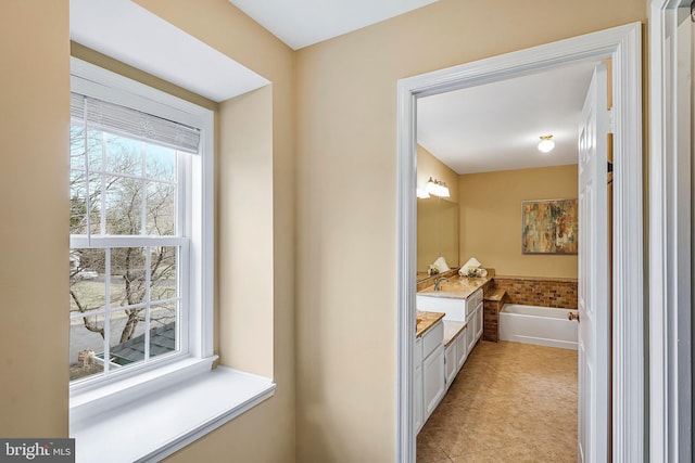 bathroom with a garden tub, vanity, and tile patterned floors