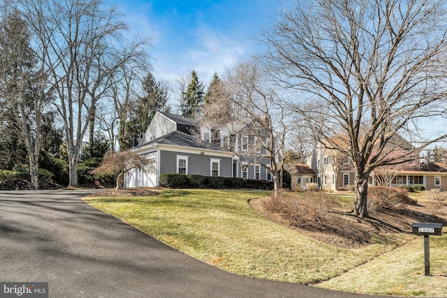 view of front of home with driveway, an attached garage, and a front lawn