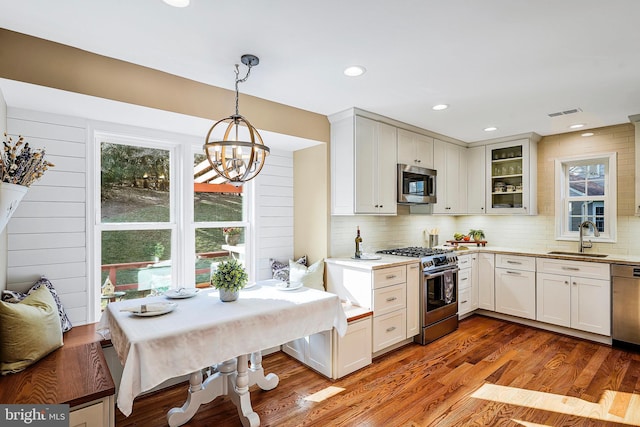 kitchen featuring stainless steel appliances, wood finished floors, a sink, and tasteful backsplash