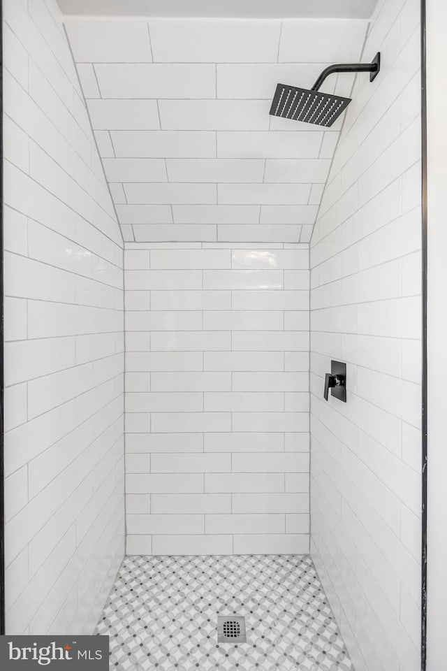 bathroom featuring lofted ceiling and tiled shower