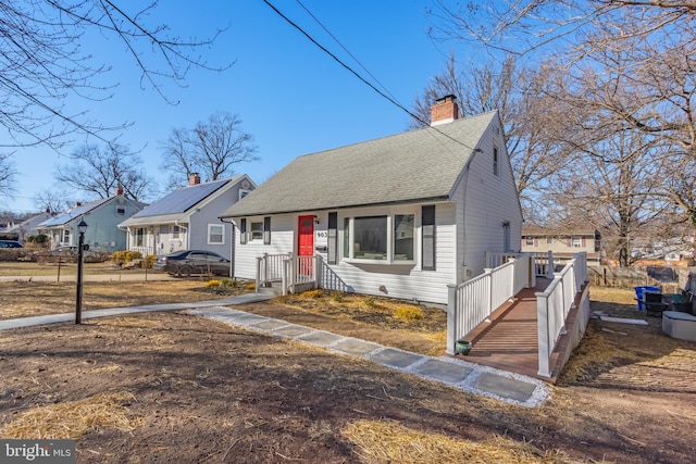 view of front of house with a shingled roof, a chimney, fence, and a residential view