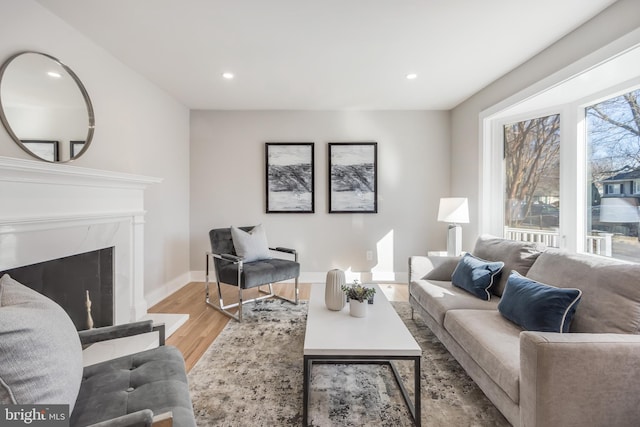 living area featuring baseboards, light wood finished floors, a fireplace, and recessed lighting