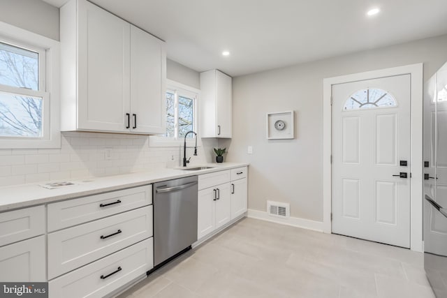 kitchen featuring visible vents, dishwasher, backsplash, white cabinetry, and a sink