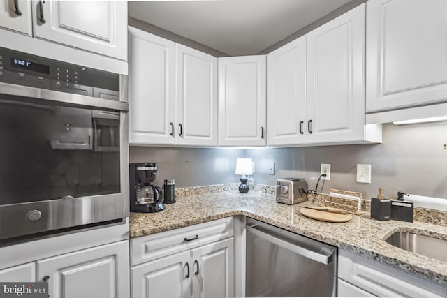 kitchen featuring stainless steel appliances, white cabinetry, and light stone countertops