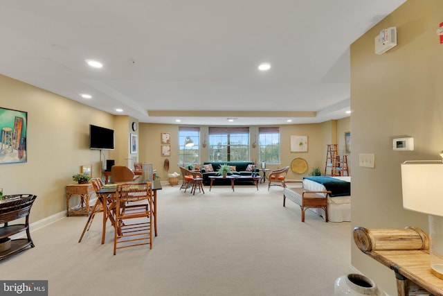 living room featuring light colored carpet and a raised ceiling