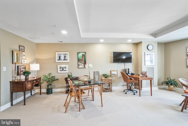 carpeted office space with a tray ceiling