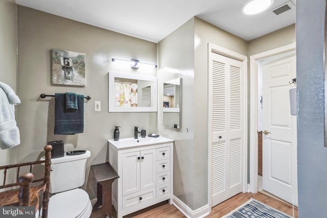 bathroom featuring wood-type flooring, vanity, and toilet