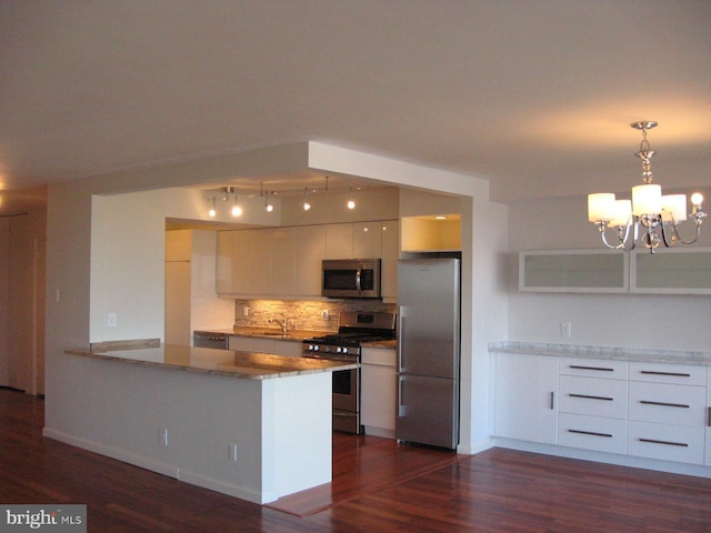 kitchen with appliances with stainless steel finishes, white cabinetry, hanging light fixtures, decorative backsplash, and dark hardwood / wood-style flooring