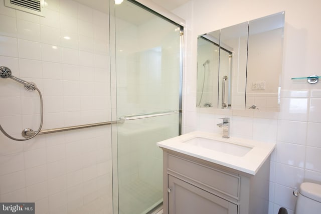 bathroom featuring an enclosed shower, vanity, toilet, and tile walls