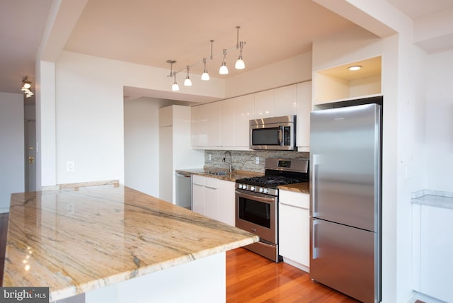 kitchen featuring light stone counters, stainless steel appliances, sink, and white cabinets