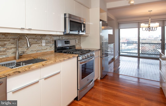 kitchen with sink, light stone counters, appliances with stainless steel finishes, dark hardwood / wood-style floors, and white cabinets