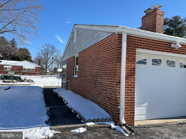 snow covered property with a garage