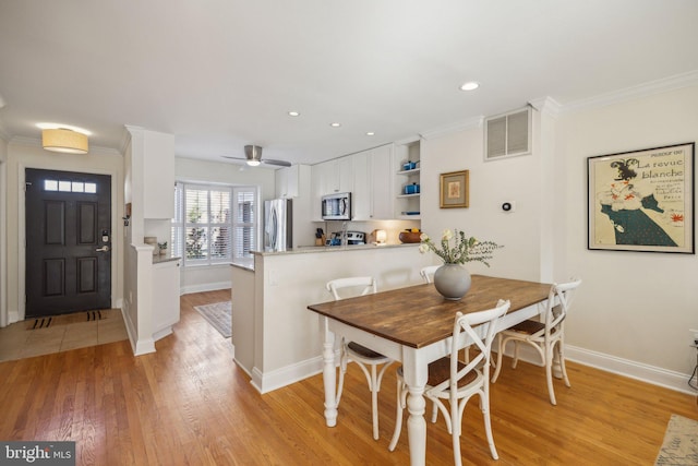 dining area with ornamental molding, ceiling fan, and light wood-type flooring