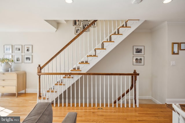 stairway with crown molding and wood-type flooring