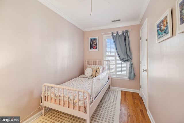 bedroom featuring crown molding and light hardwood / wood-style flooring