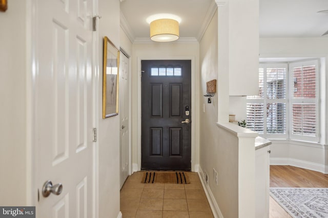 entryway with crown molding and light tile patterned flooring