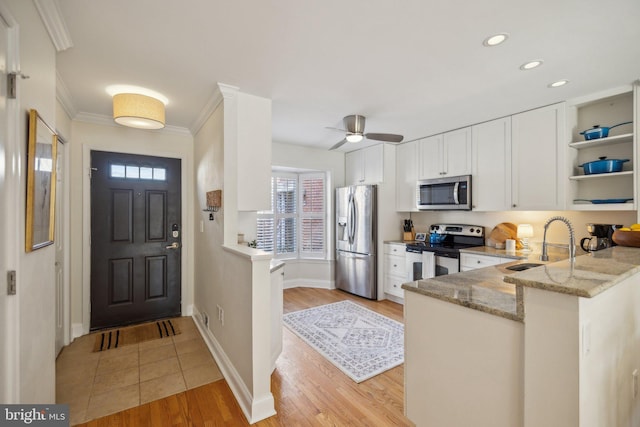 kitchen featuring white cabinetry, stainless steel appliances, light stone counters, kitchen peninsula, and light wood-type flooring