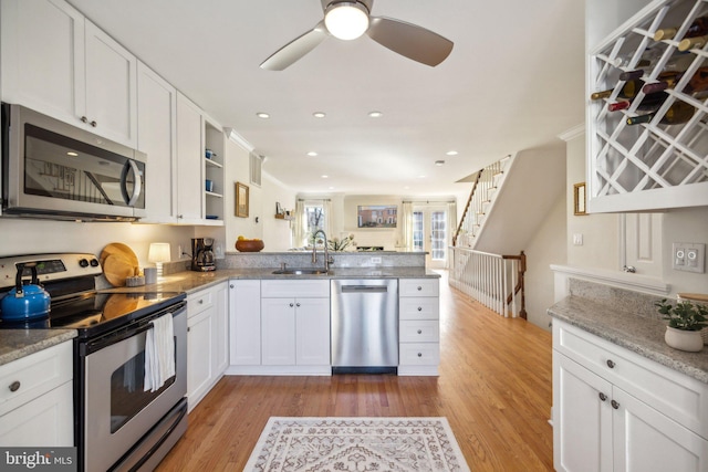 kitchen featuring white cabinetry, appliances with stainless steel finishes, kitchen peninsula, and sink