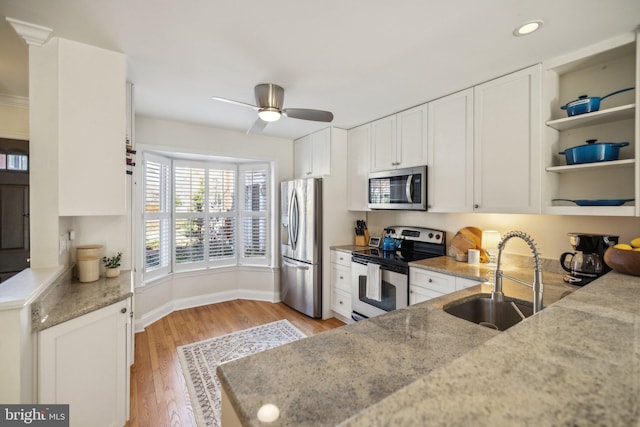 kitchen with appliances with stainless steel finishes, light stone countertops, sink, and white cabinets