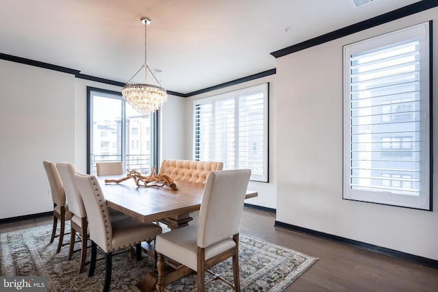 dining area featuring dark wood finished floors, crown molding, visible vents, an inviting chandelier, and baseboards