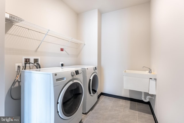 laundry area featuring light tile patterned floors, a sink, separate washer and dryer, laundry area, and baseboards