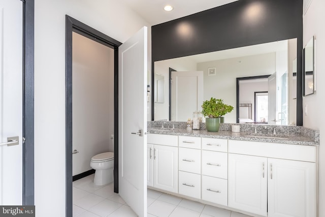 full bath featuring double vanity, tile patterned flooring, toilet, and a sink