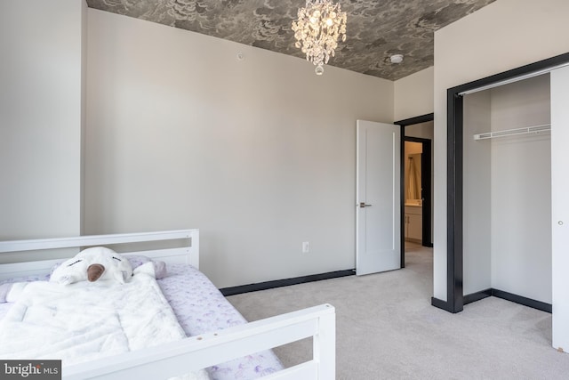 bedroom featuring carpet, baseboards, a chandelier, and a closet