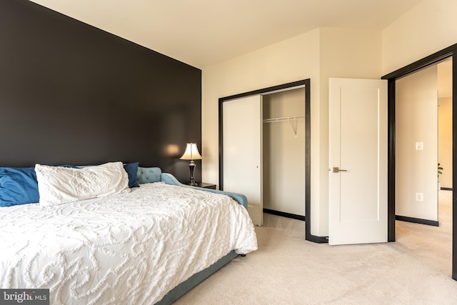 bedroom with a closet, light carpet, and baseboards