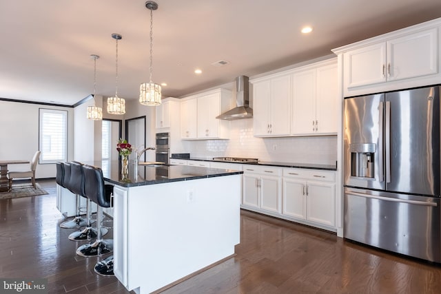 kitchen featuring wall chimney exhaust hood, a breakfast bar, dark wood-style flooring, stainless steel appliances, and backsplash