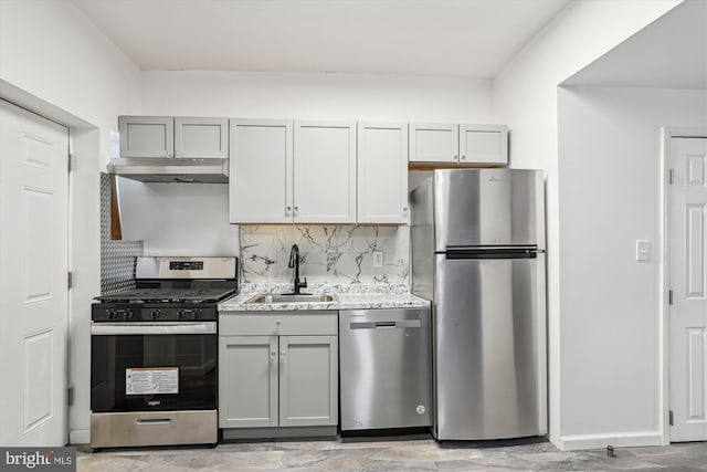 kitchen featuring sink, backsplash, light stone counters, gray cabinets, and stainless steel appliances