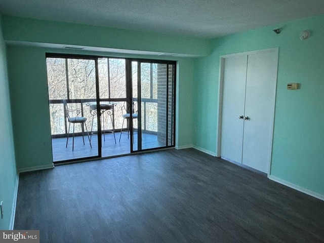 spare room featuring dark hardwood / wood-style floors and a textured ceiling