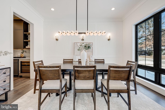 dining space with crown molding, beverage cooler, and light hardwood / wood-style floors