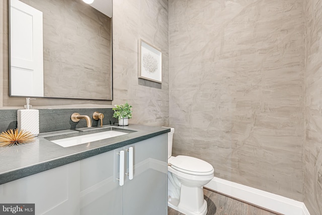 bathroom featuring hardwood / wood-style flooring, vanity, tile walls, and toilet