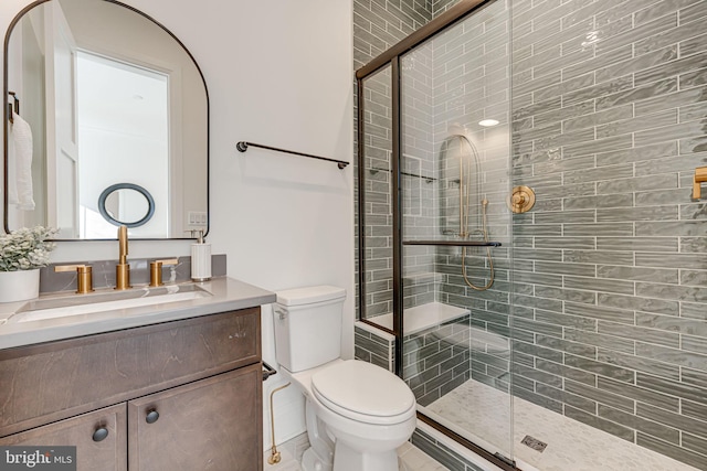 bathroom with a shower with door, vanity, and toilet