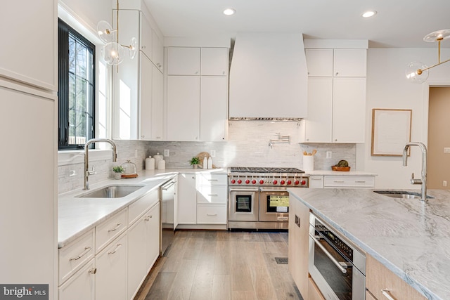 kitchen with pendant lighting, sink, stainless steel appliances, and white cabinets