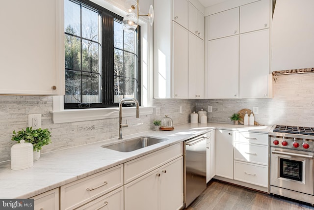 kitchen with appliances with stainless steel finishes, white cabinetry, wood-type flooring, sink, and backsplash